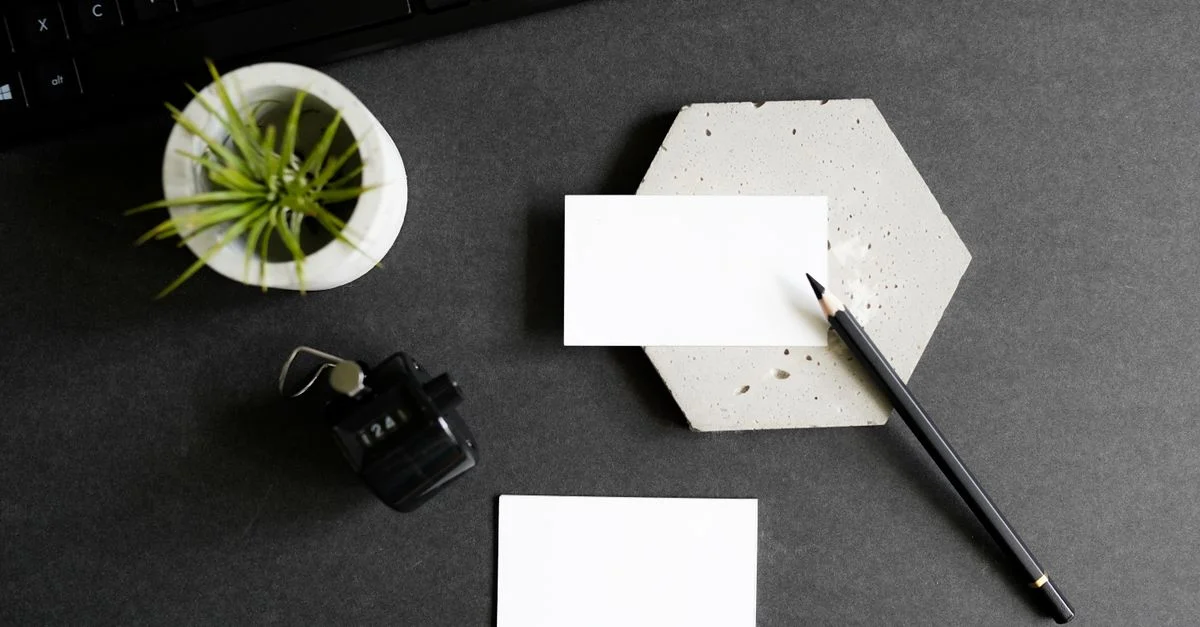 Vue de haut d'un bureau élégant avec des cartes de visite, un clavier, un crayon et une petite plante d'intérieur.