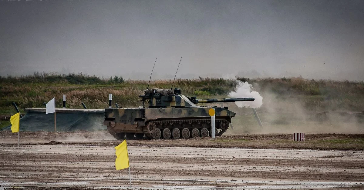 Un char militaire tirant un obus pendant un entraînement dans un champ ouvert.