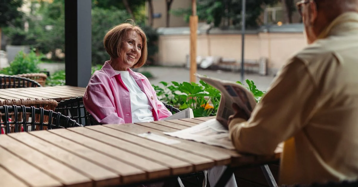 Un couple âgé partage un moment joyeux dans un café en plein air, embrassant l'amour et la complicité.