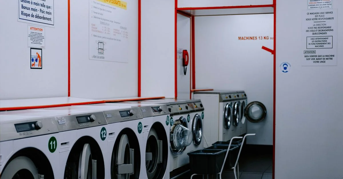 À l'intérieur d'une laverie avec des lave-linge alignés contre le mur.