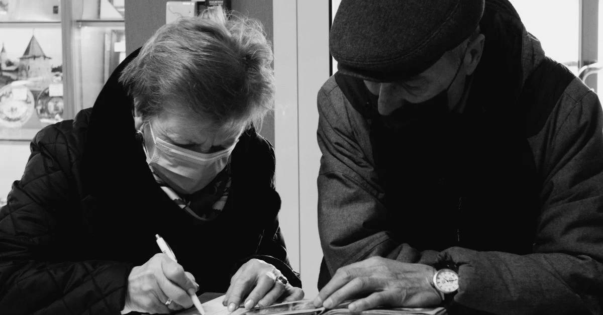 Photo en noir et blanc d'un couple âgé effectuant un travail administratif avec des masques faciaux.