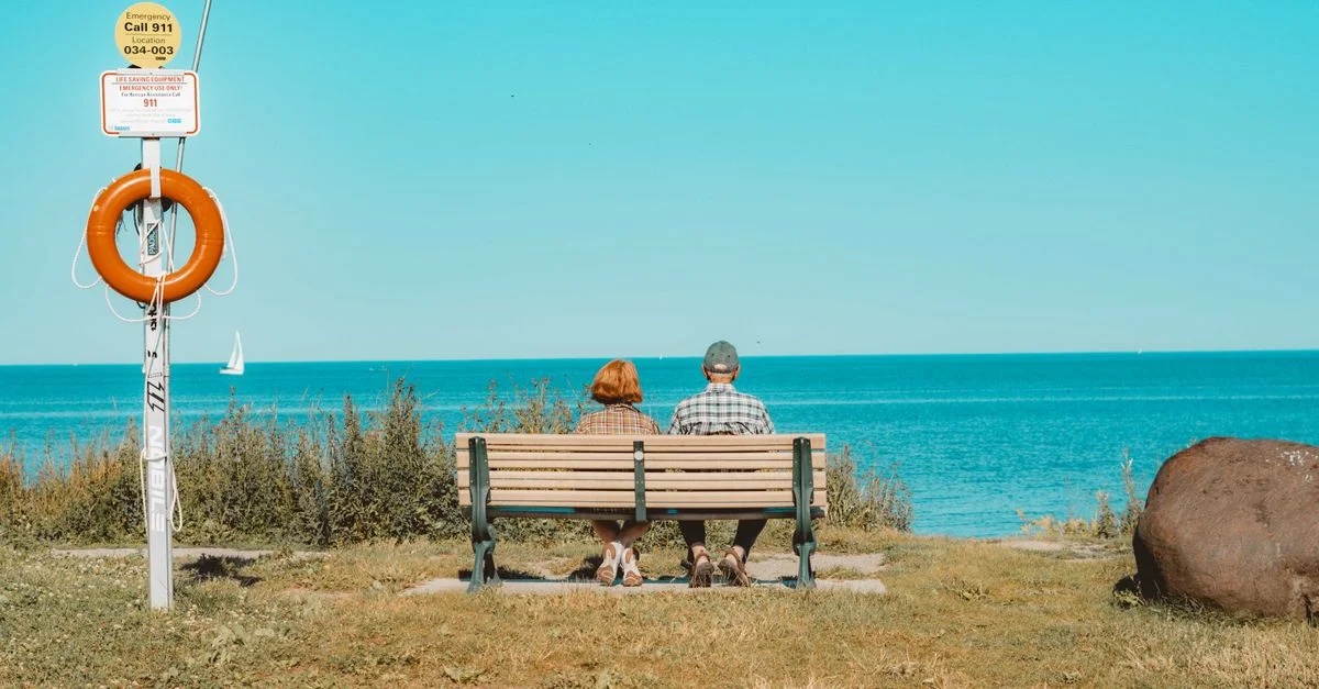 Un couple senior assis sur un banc profitant d'une journée ensoleillée au bord du Lac Ontario à Toronto.
