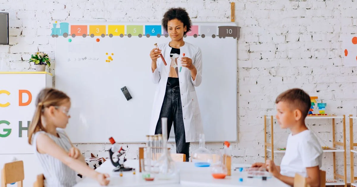 Des enfants réalisent une expérience scientifique sous l'œil d'un enseignant dans une salle de classe.